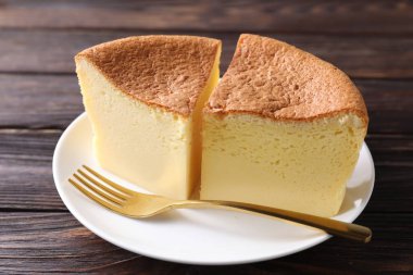 Pieces of tasty Japanese Castella sponge cake and fork on wooden table, closeup