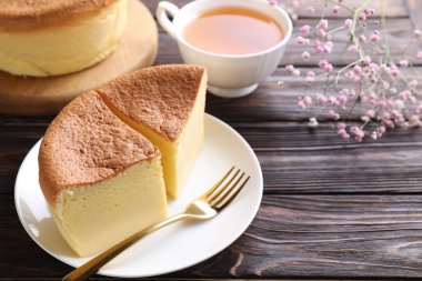 Lezzetli Japon Castella sünger keki, çay, çingene çiçekleri ve ahşap masa çatalı, yakın plan. Metin için boşluk