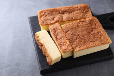 Tasty Japanese Castella sponge cake on grey table, closeup. Space for text