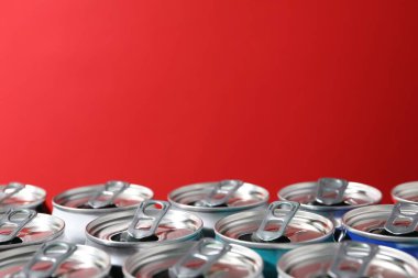 Kırmızı arka planda birçok alüminyum içecek kutusu, yakın plan. Metin için boşluk