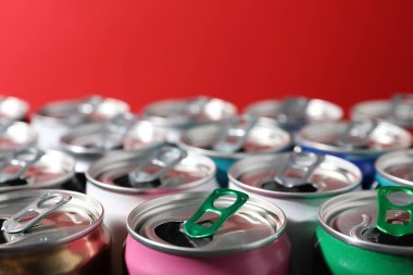 Kırmızı arka planda birçok alüminyum içecek kutusu, yakın plan