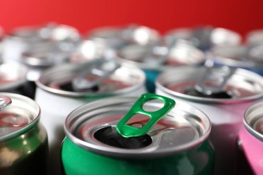 Kırmızı arka planda birçok alüminyum içecek kutusu, yakın plan