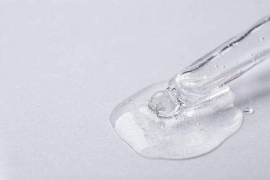 Işıklı arka planda kozmetik serumu olan bir boru, yakın plan. Metin için boşluk
