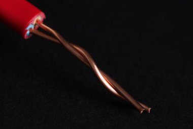 Siyah arkaplanda kırmızı şeritli elektrik kablosu, yakın plan.