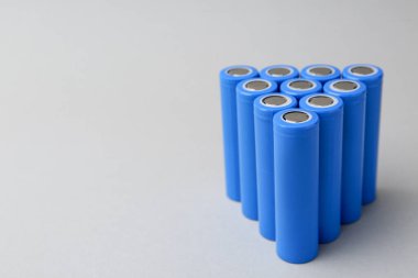 Açık gri arka planda birçok AA cep telefonu pili var, yakın plan. Metin için boşluk