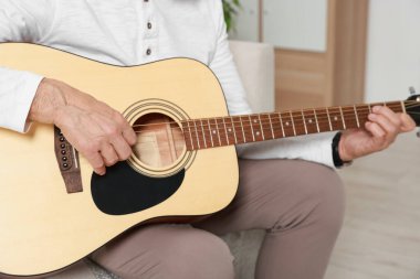 Rahatlatıcı hobi. Son sınıf öğrencisi evde gitar çalıyor, yakın plan.
