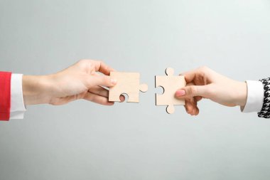 İş stratejisi ve takım çalışması konsepti. Ortaklar bulmaca parçalarını gri arkaplanda birleştiriyor, yakın plan