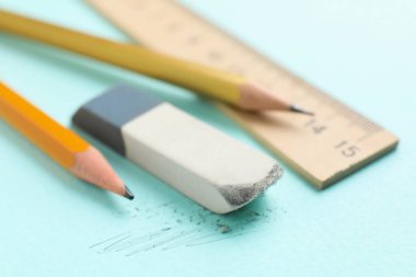 Eraser, pencils and ruler on light blue background, closeup