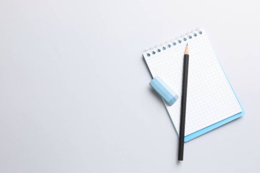 Eraser, pencil and notepad on light background, top view. Space for text