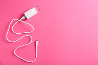 Pembe arka planda şarj kablosu olan USB güç adaptörü, üst görüş. Metin için boşluk