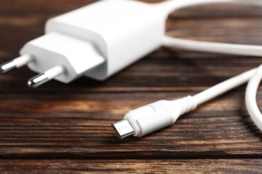 Tahta masada şarj kablosu olan USB güç adaptörü, yakın plan.