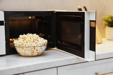 Beyaz mermer tezgahta mikrodalga fırının yanındaki kasede lezzetli patlamış mısır.