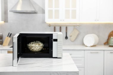 Mikrodalga fırını aç. Mutfaktaki beyaz mermer masada patlamış mısır kasesi var. Mesaj için yer var.