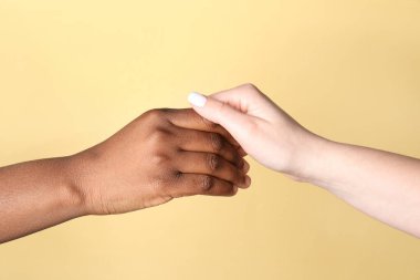 Irkçılığı bırak. Bej arka planda el ele tutuşan farklı ten renginde insanlar, yakın plan