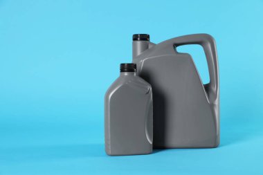 Grey plastic canisters on light blue background, space for text