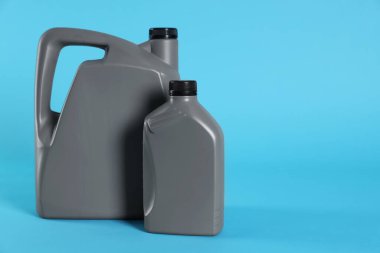 Grey plastic canisters on light blue background, space for text