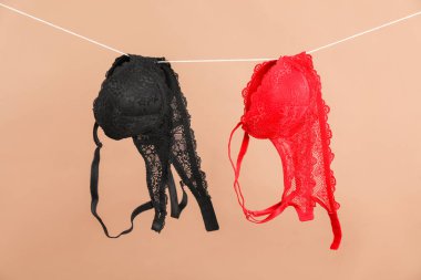 Beautiful bras hanging on rope against dark beige background