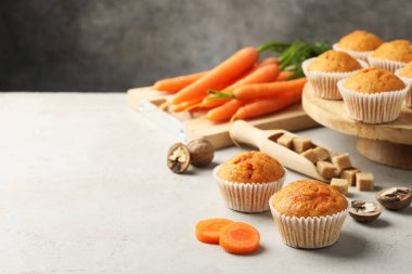 Lezzetli havuçlu kekler, taze sebzeler, şeker ve cevizler açık gri masada, yakın plan. Metin için boşluk