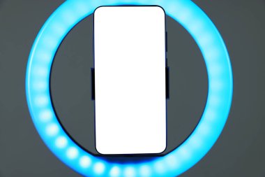 Gri arkaplanda akıllı telefonu olan halka lambası, yakın plan