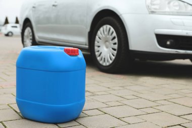 Light blue plastic canister on pavement outdoors