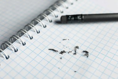 Pencil with eraser and scraps on notepad, selective focus