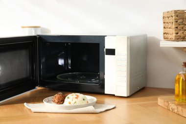 Mikrodalga fırını aç, pilav ve tavukla birlikte ahşap masa içinde.