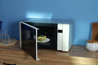 Mikrodalga fırını lazanya ve mutfak gereçleri ile aç.