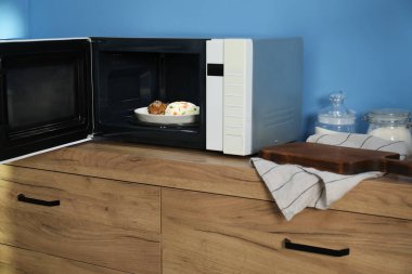 Mikrodalga fırını aç, pilav ve tavukla birlikte ahşap dolapta.