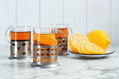 Glasses of tea in metal holders served on white marble table, closeup