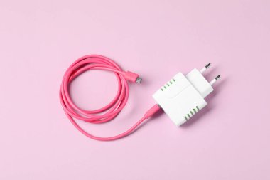 Pembe arka planda şarj kablosu olan USB güç adaptörü, üst görünüm
