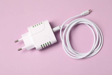 Pembe arka planda şarj kablosu olan USB güç adaptörü, üst görünüm