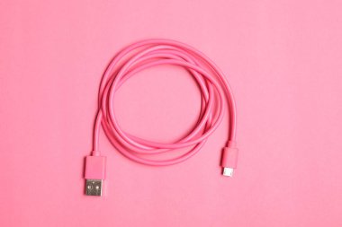 One USB charge cable on pink background, top view