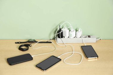 Kabloları elektrik kablosuna takılı USB adaptörleri tahta masadaki şarj cihazları, yakın plan