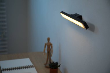 Modern LED lamp on wall above desk, closeup
