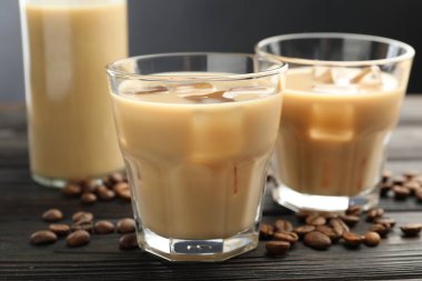 Bardakta kremalı kahve likörü ve ahşap masada fasulye, yakın plan.