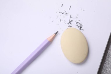 Eraser, pencil, notebook and scraps on table, top view
