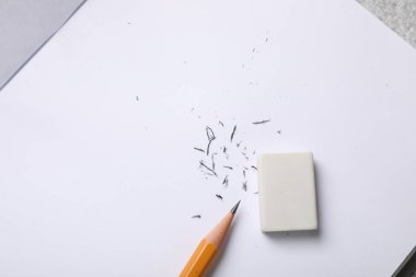 Eraser, pencil, notebook and scraps on table, top view