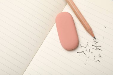 Eraser, pencil and scraps on lined notebook sheet, flat lay, Space for text