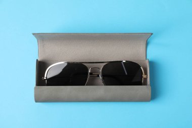 Açık mavi arkaplanda şık güneş gözlüklü çanta, üst görünüm