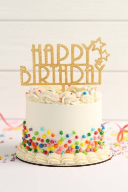 Delicious bento cake with colorful sprinkles, topper and serpentine streamer on white table