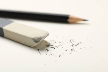 Eraser, pencil and scraps on white sheet of paper, closeup