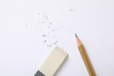 Eraser, pencil and scraps on white background, flat lay