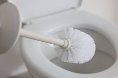 Toilet brush and bowl indoors, selective focus