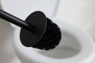Black toilet brush and bowl indoors, selective focus