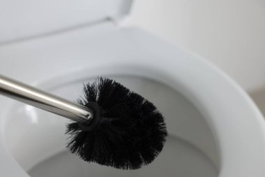 Black toilet brush and bowl indoors, selective focus