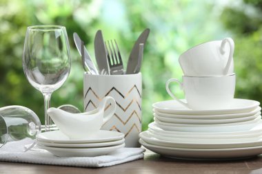 Clean dishware on wooden table against blurred background