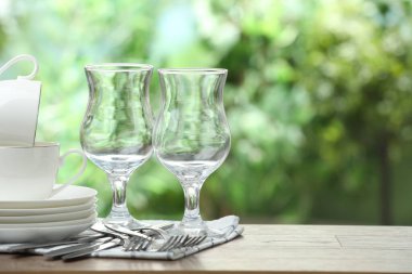 Clean dishware on wooden table against blurred background. Space for text