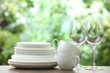 Clean dishware on wooden table against blurred background. Space for text