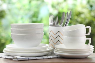 Clean dishware on wooden table against blurred background