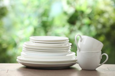 Clean dishware on wooden table against blurred background. Space for text